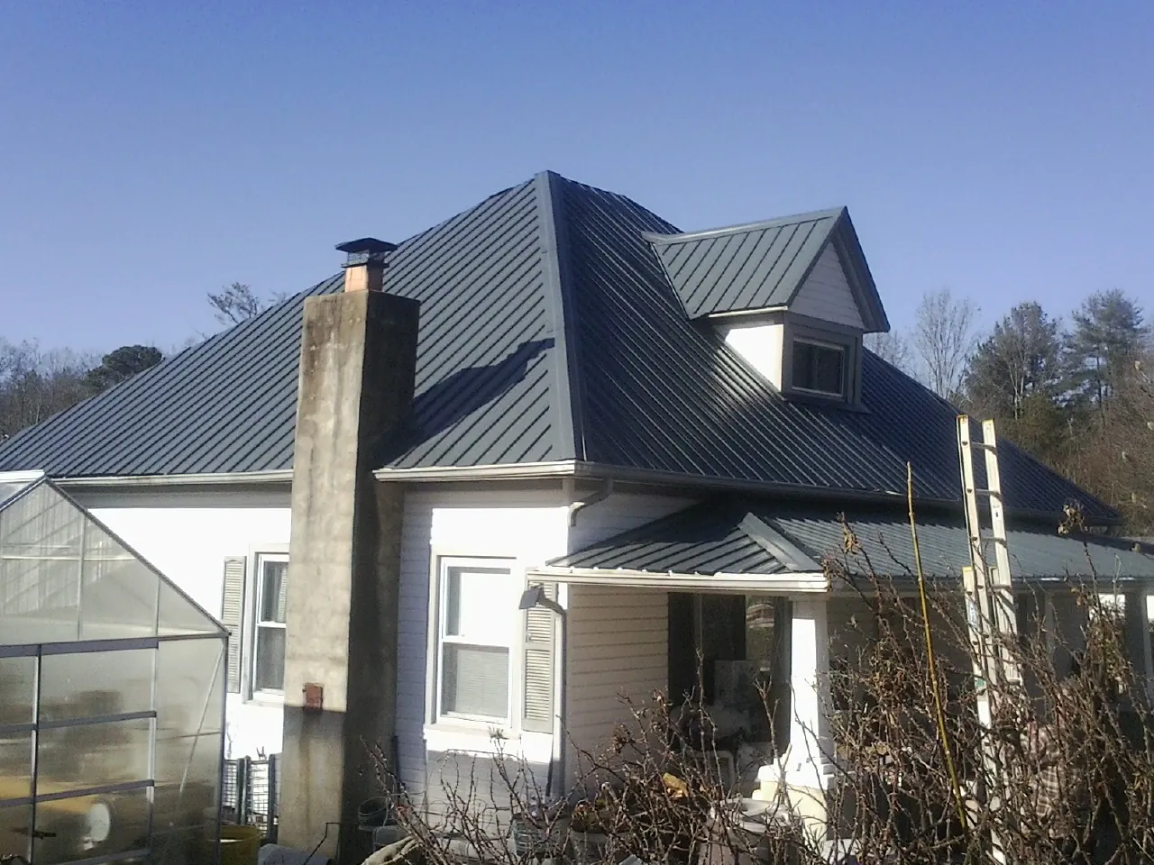 Dark blue standing seam metal roof on a white farmhouse with dormer — Slate & Tile Roof Repair by Roofing Brothers in Pennsylvania Furnace