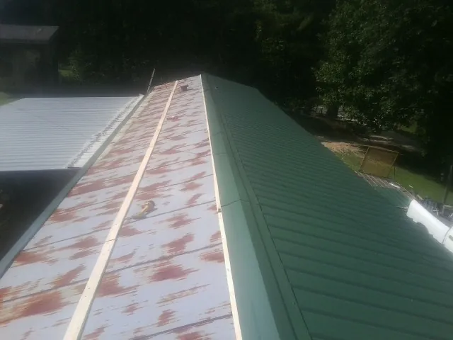 Old rusted panels beside newly installed green metal roofing — Wind Damage Roof Repair by Roofing Brothers in Pennsylvania Furnace