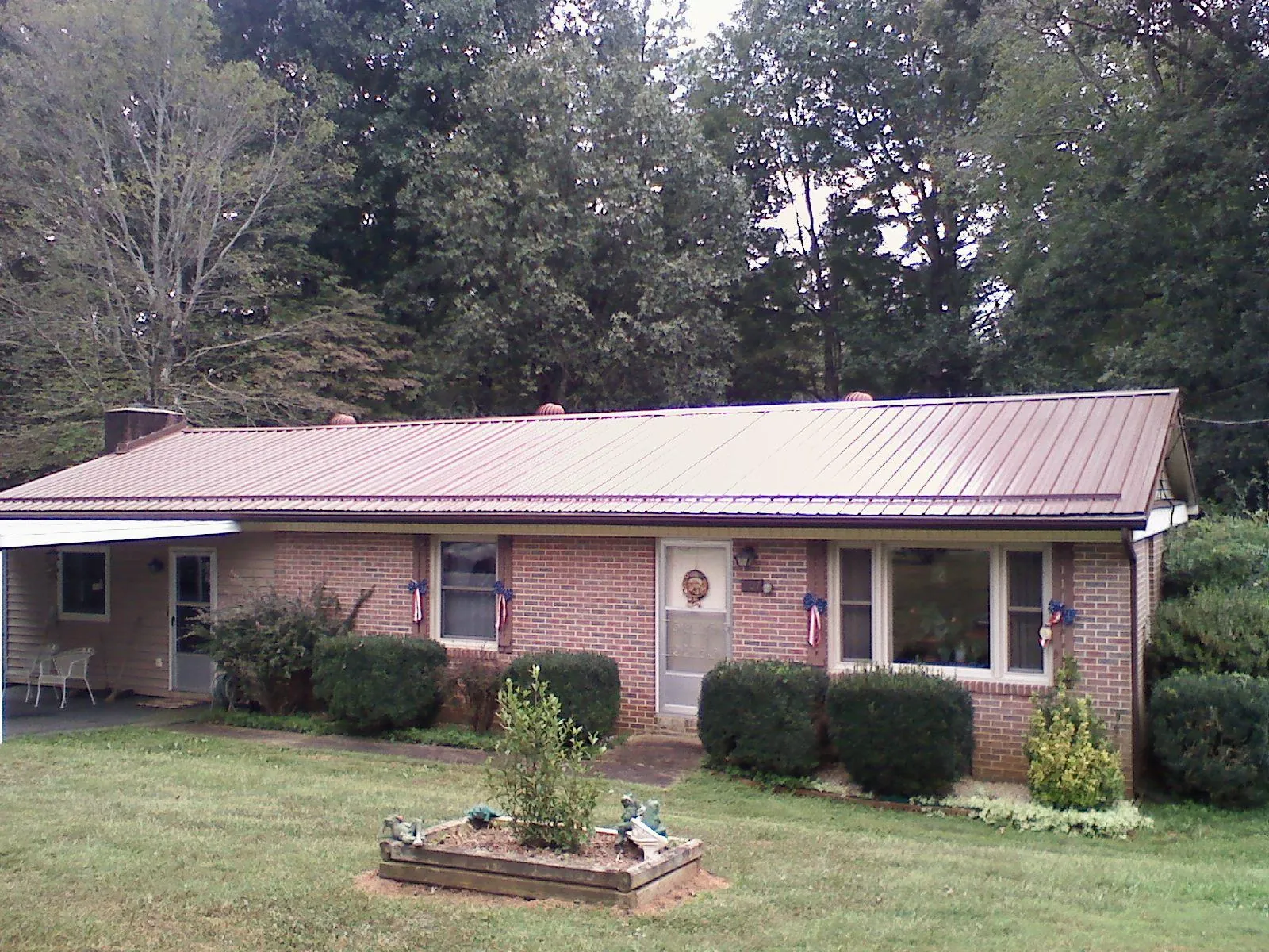 Bronze metal roof on a brick ranch home with a carport in Pennsylvania Furnace