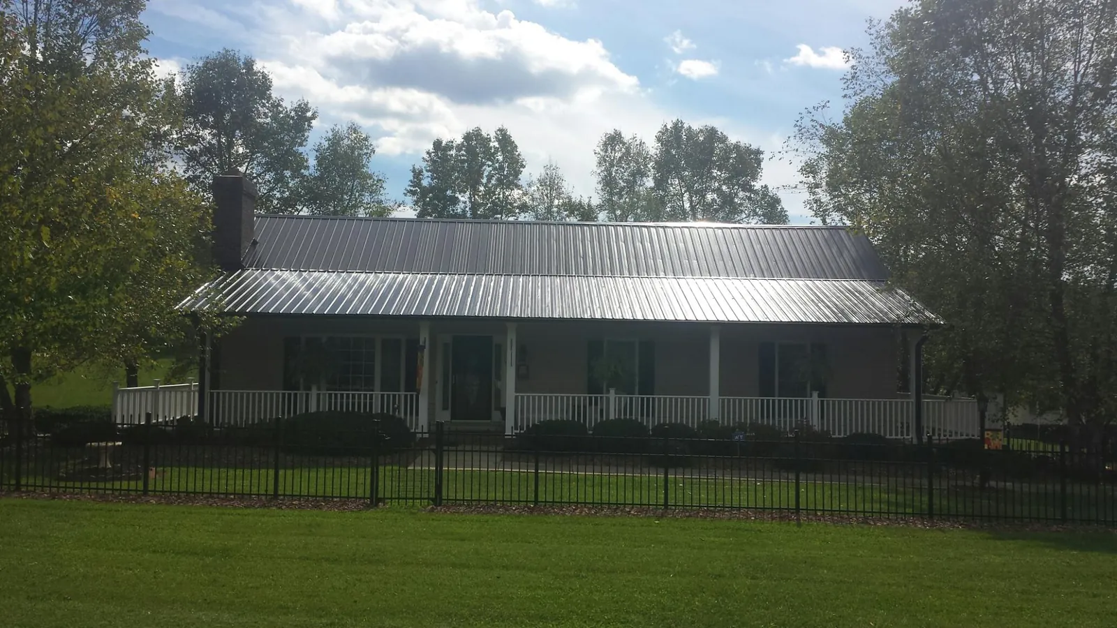 Gray metal roof on a brick ranch with a full width front porch — Gutter Guard Installation work by our crew in Pennsylvania Furnace