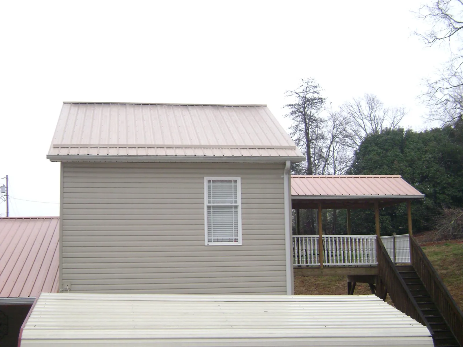 Tan metal roofs on a two story addition and attached porch, from a Roof Replacement job in Pennsylvania Furnace