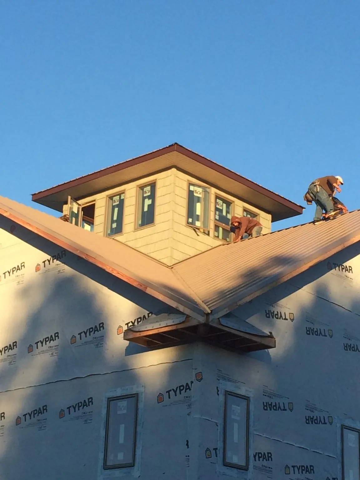 Roofers working around a rooftop cupola on a new metal roof at sunset — Roof Waterproofing in Pennsylvania Furnace by Roofing Brothers